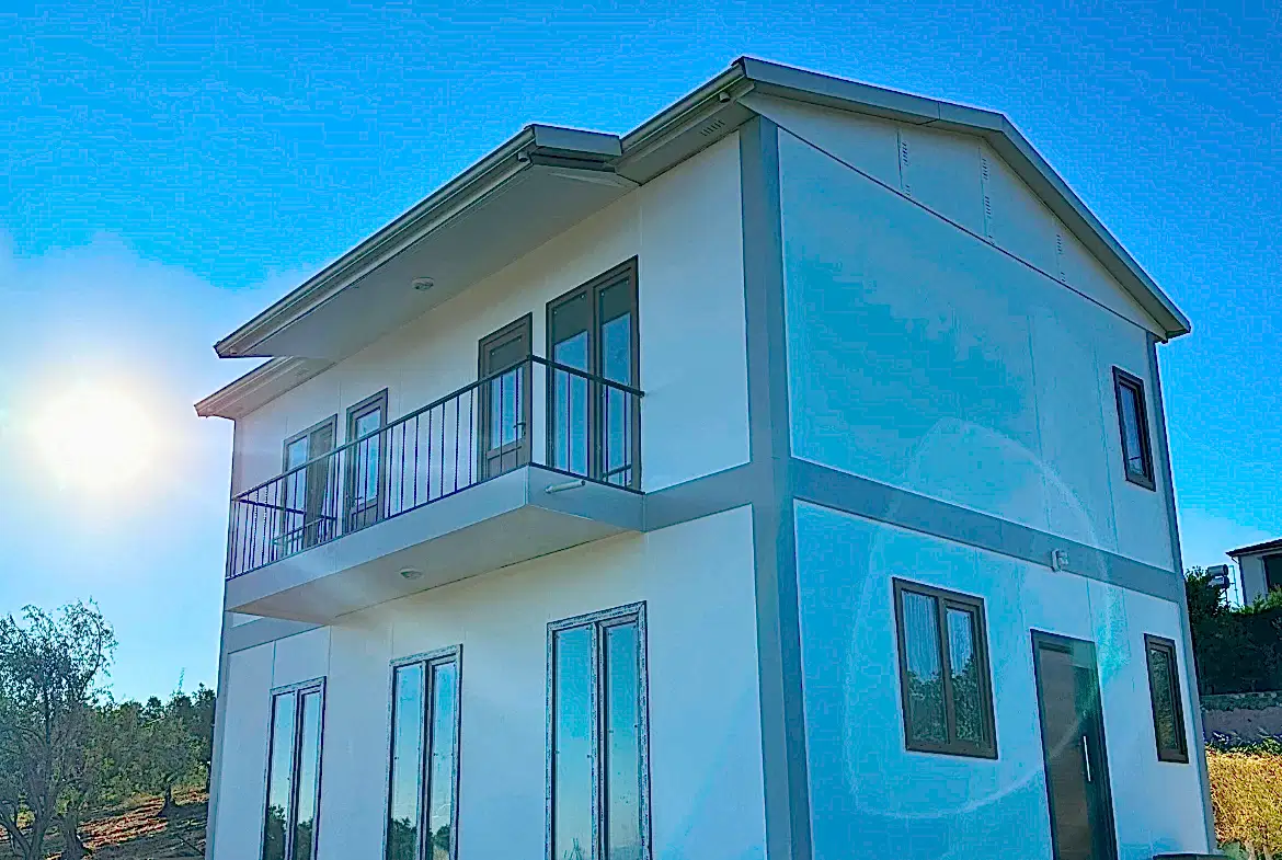 Balkonlu beyaz dış cepheli iki katlı prefabrik ev
